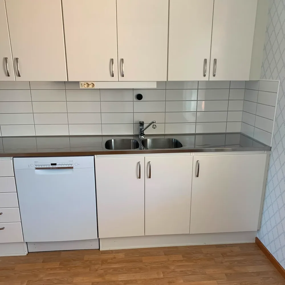 Rengjort kök med diskbänk, skåpluckor och vitvaror efter flyttstädning